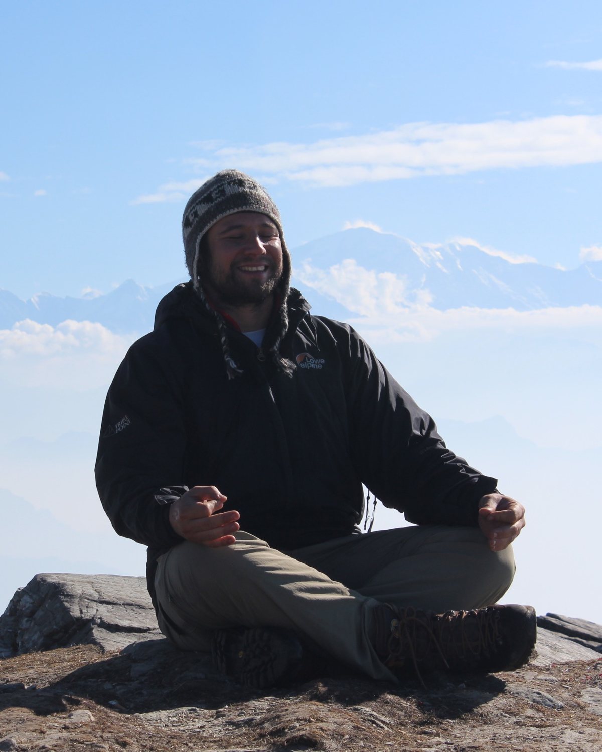Prof. Daniel De Nardi meditando no alto de uma montanha, com o Himalaia ao fundo
